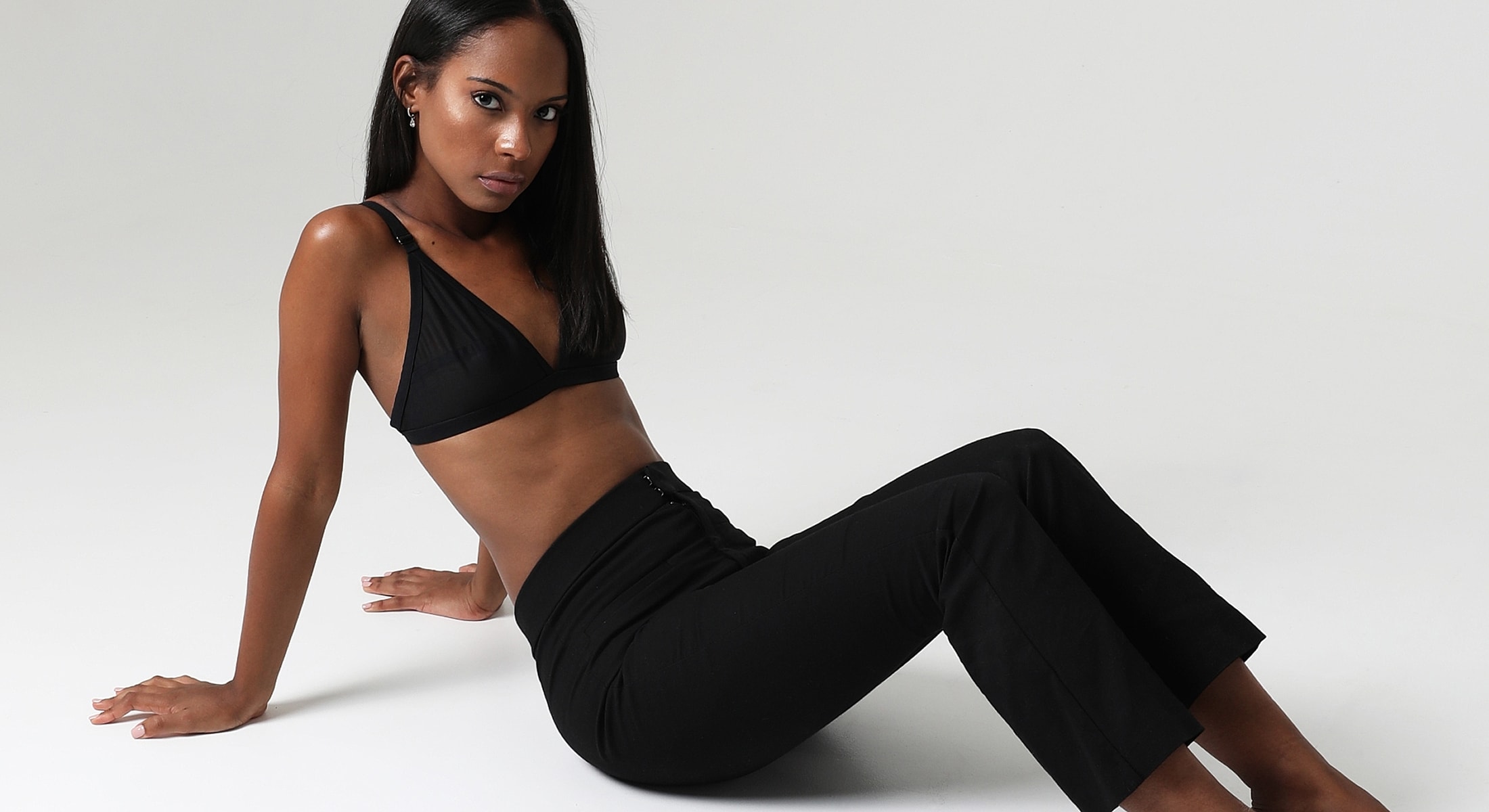 Abuja Female Wellness Model sitting in stylish black attire.